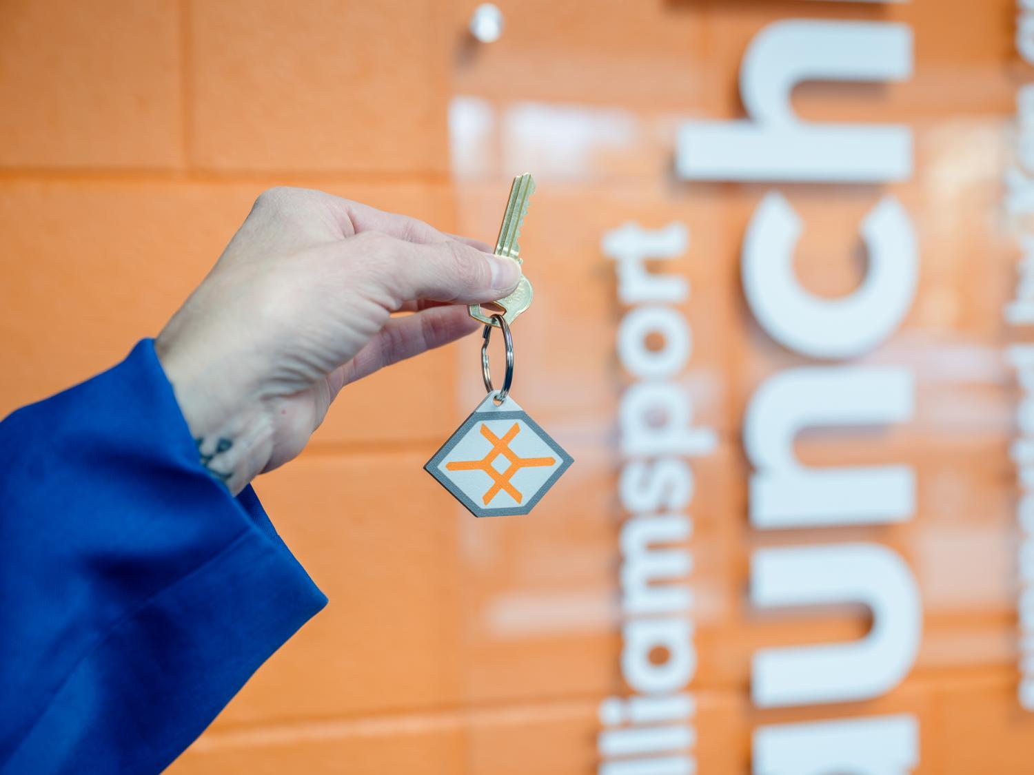 A hand holding up a key with a launchbox logo fob