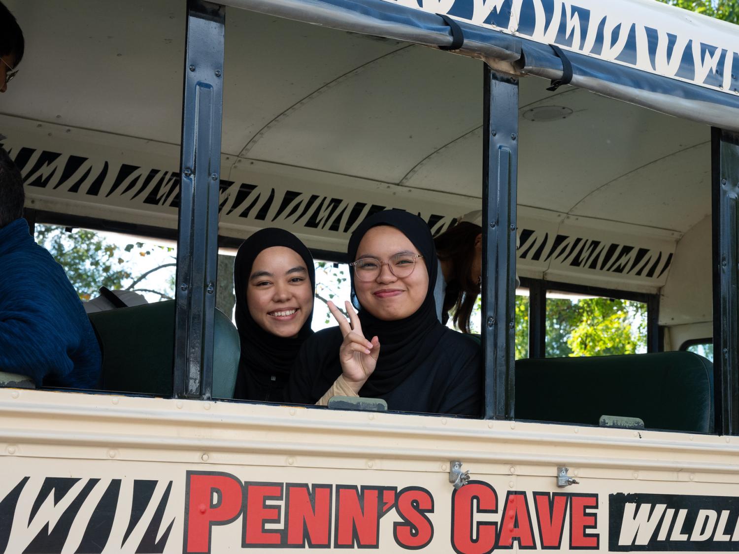 Two students smiling from inside a bus