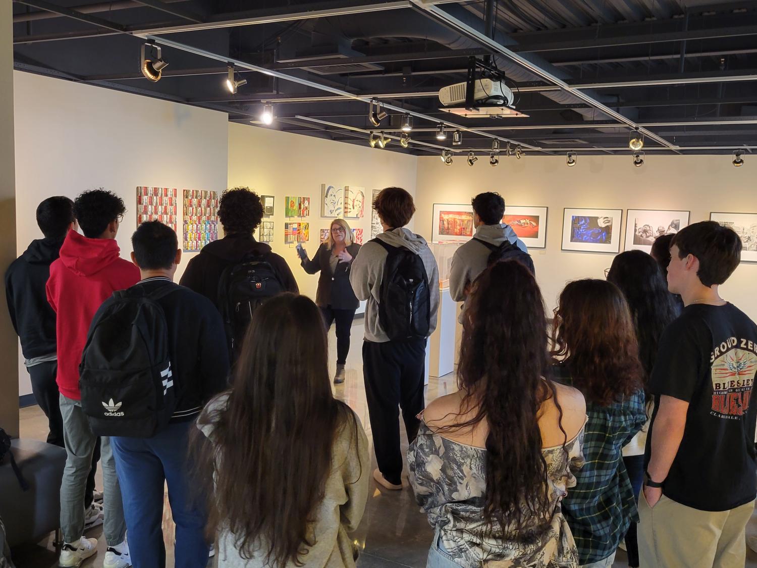 students gathered listening to a speaker in an art gallery
