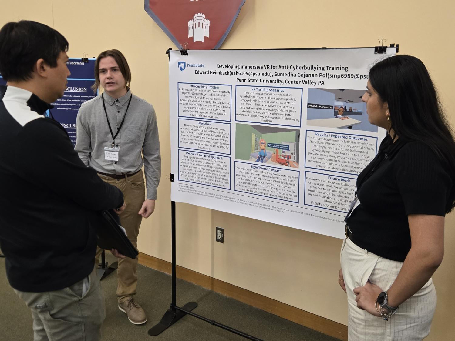 students standing in front of a poster speaking to a guest