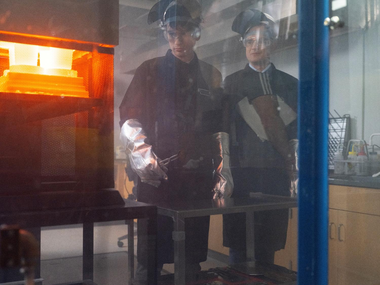 two people stand near a furnace 