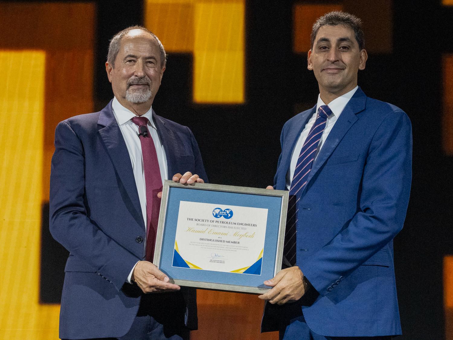 Hamid Emami-Meybodi on stage receiving award from SPE president.