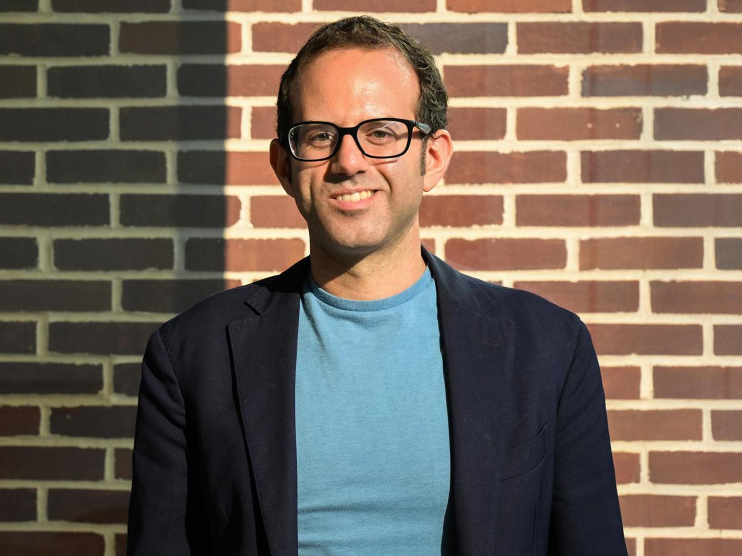 Stefano Terlizzi poses near a brick wall for a headshot.