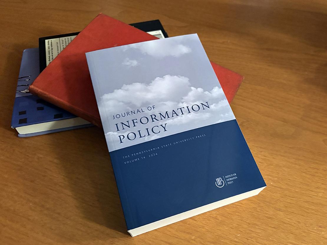 Cover of the 14th edition of the Journal of Information Policy on a wooden desk. 