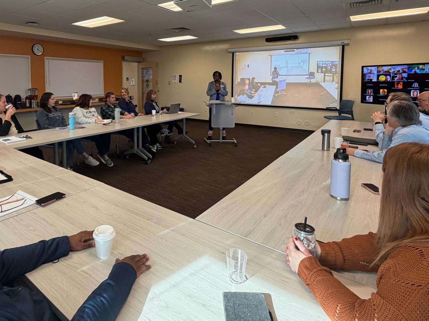people sitting around a classroom listening to a speak in the front of the room