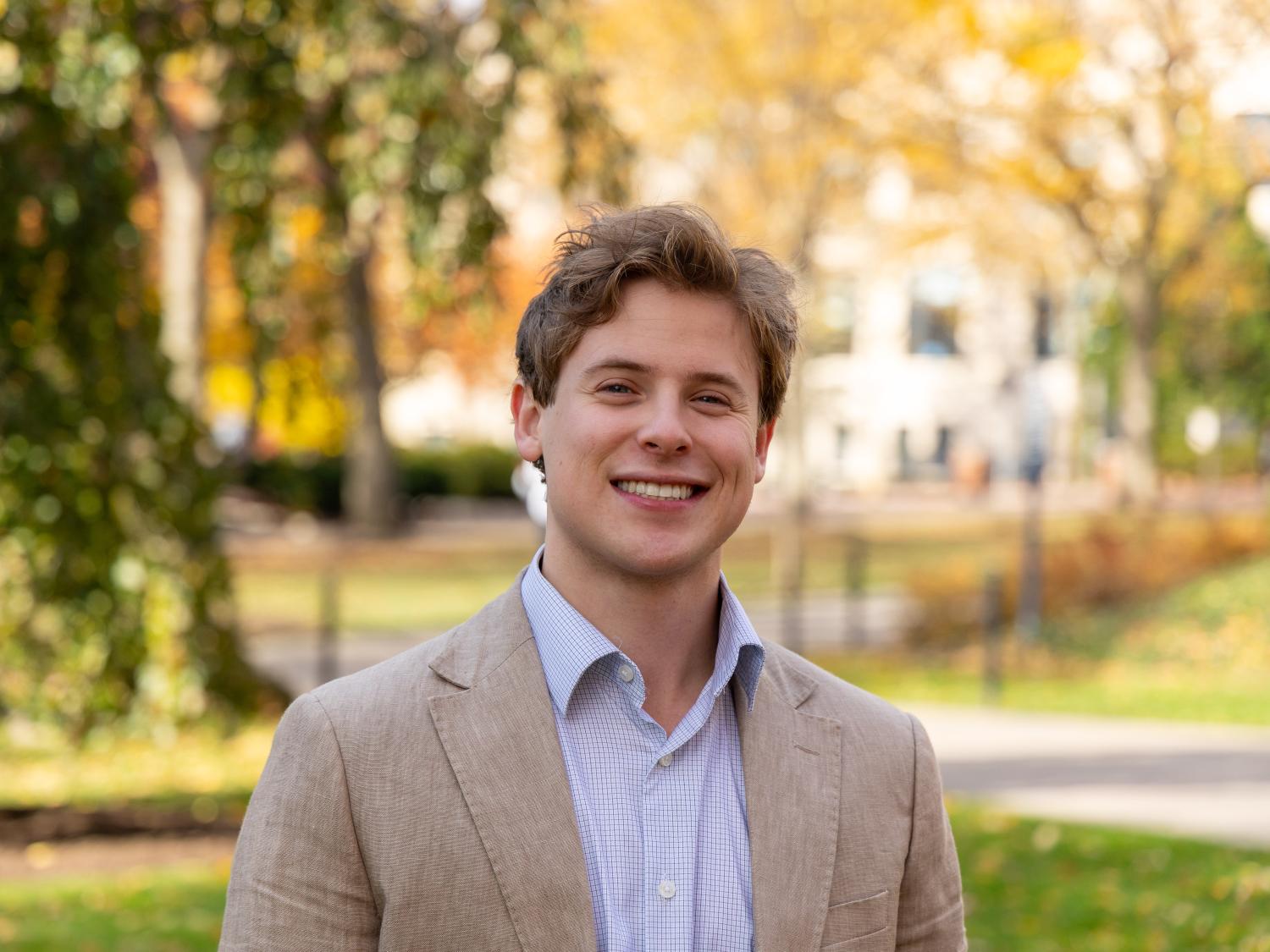 David Gross stands in front of trees during autumn at Penn State University Park.
