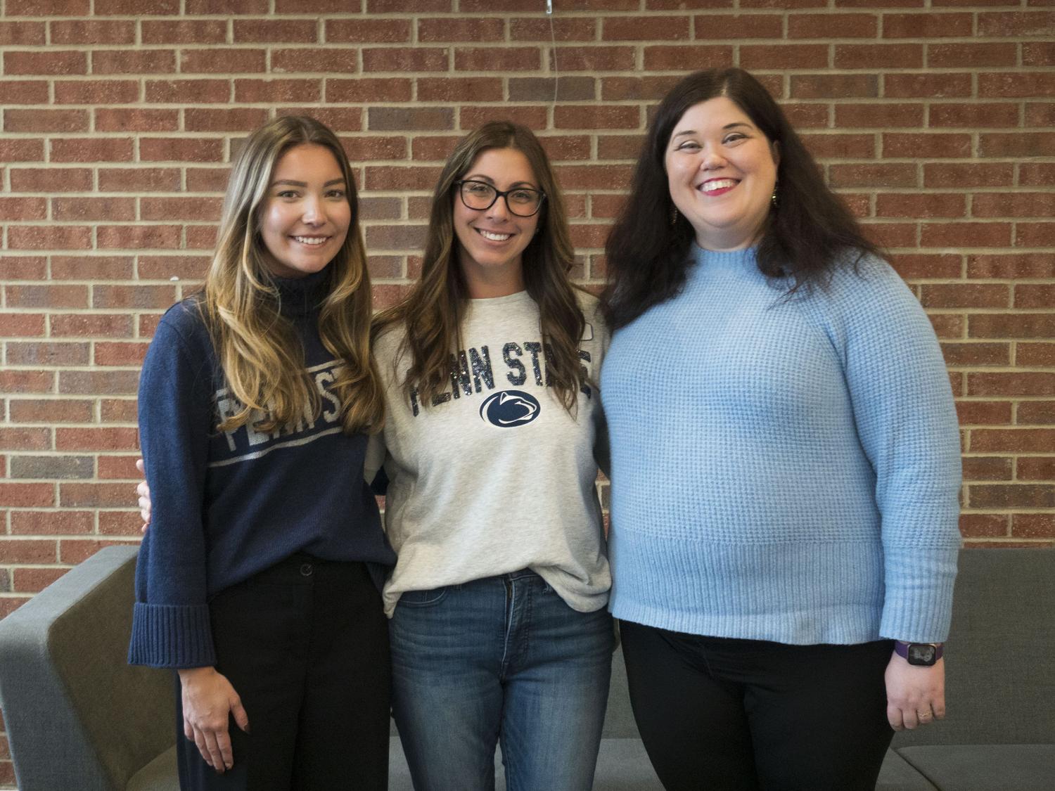 three women participants in event pose for a photo with a brick wall in the background