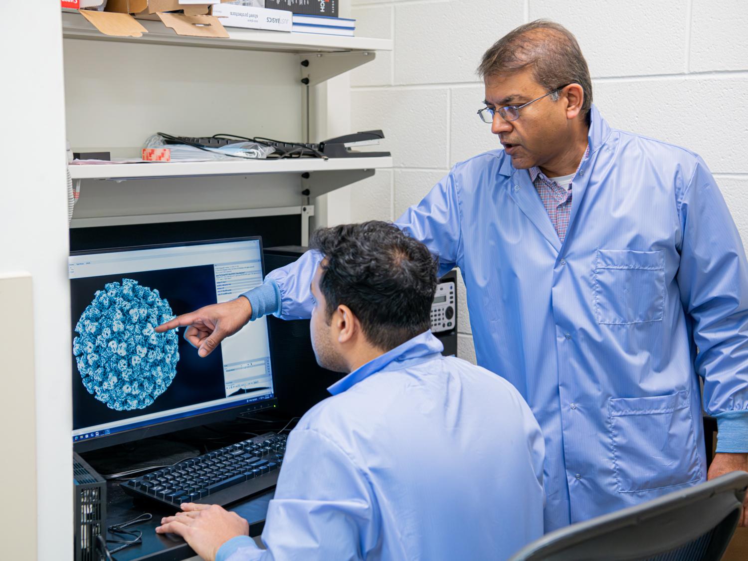 two researchers look at image of virus on computer