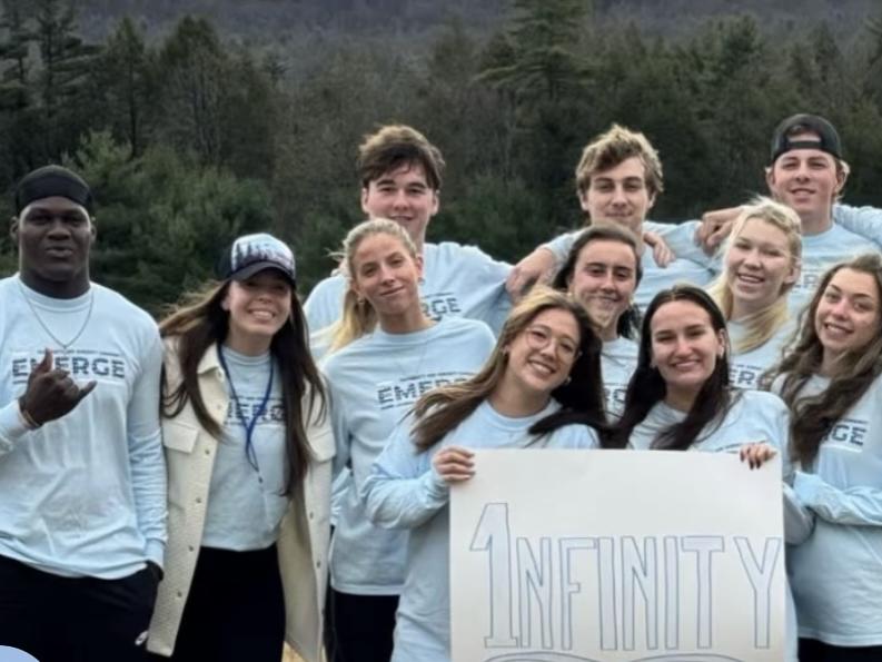 A group of smiling students wearing EMERGE t-shirts