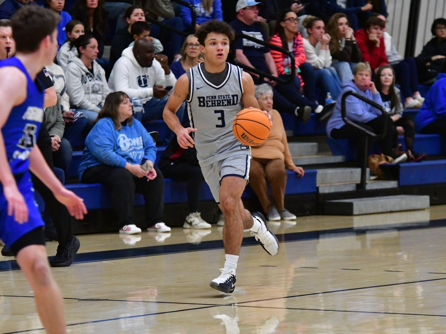 A member of the Penn State Behrend men's basketball team dribbles the ball.