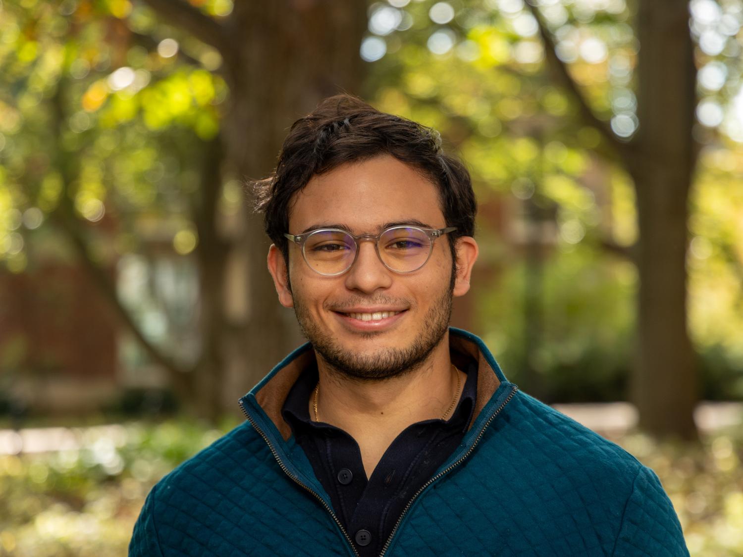 Penn State student Miguel Morazan stands in front of trees at Penn State University Park.