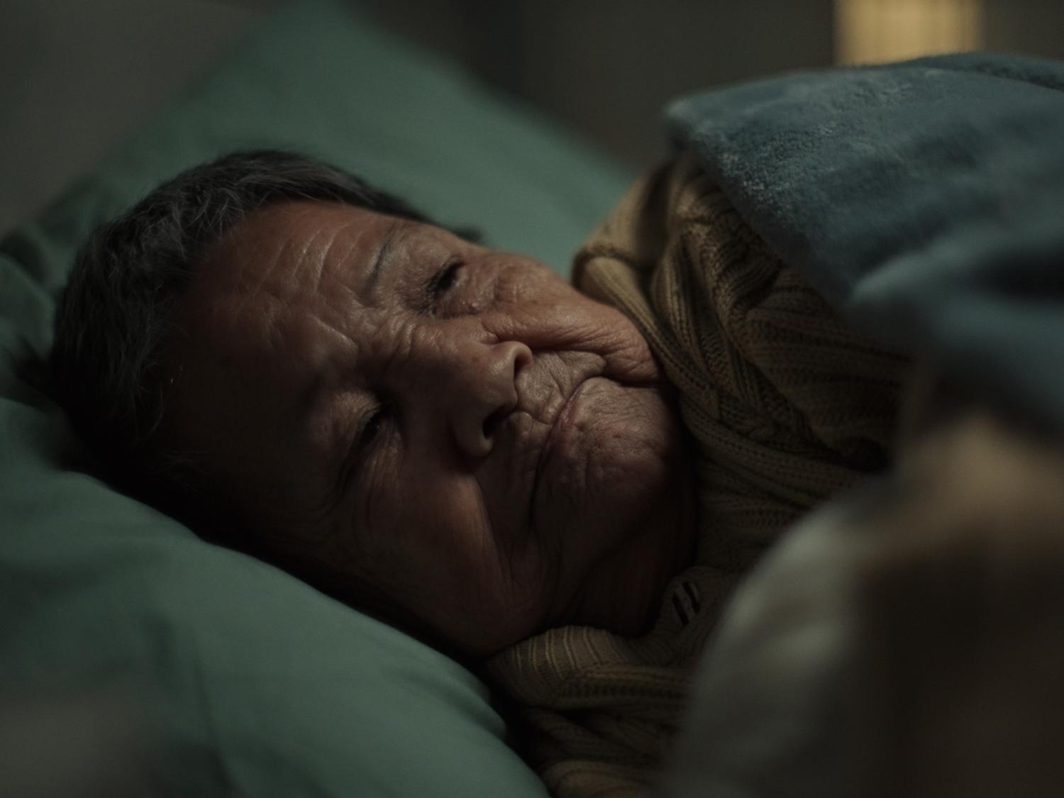 Close up of elderly person lying awake in bed in a dark room