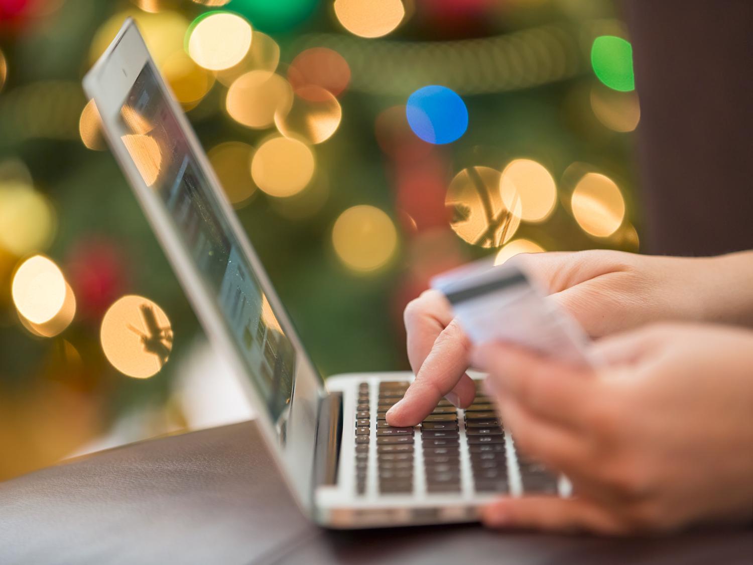 close up of a laptop computer and a hand holding a credit card