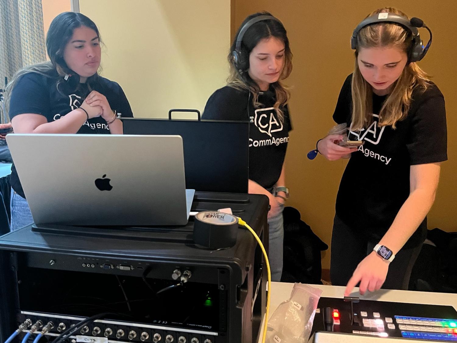 Three students working at a media station with computers, sound system, etc.