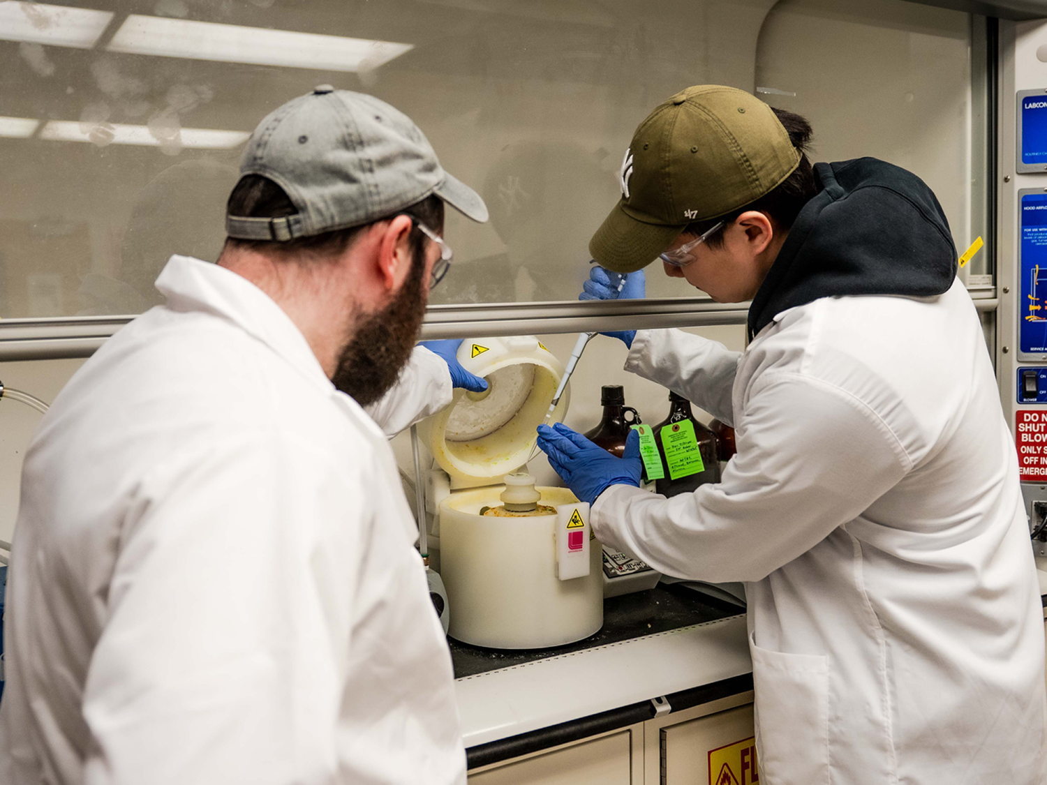 Dor Tillinger, doctoral candidate of mechanical engineering, and Donbae Lee, doctoral candidate of engineering science and mechanics, dressed in lab coats using lab equipment.
