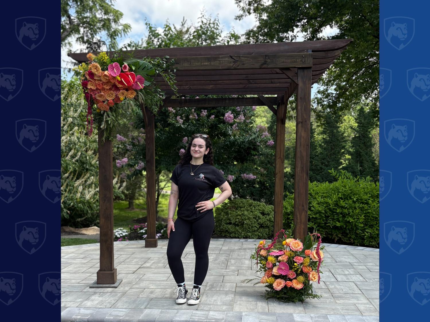 woman standing under wooden arbor with flowers