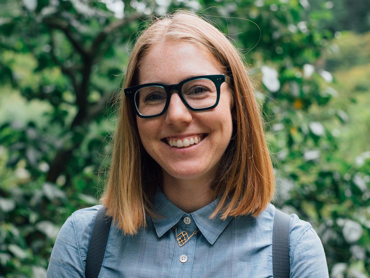 Heidi Biggs has shoulder-length hair and glasses, wearing a blue shirt with a decorative collar pin.