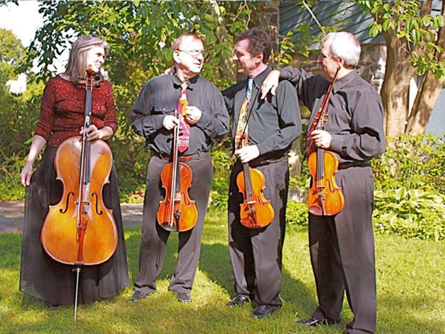 four people standing in the sun holding musical instruments