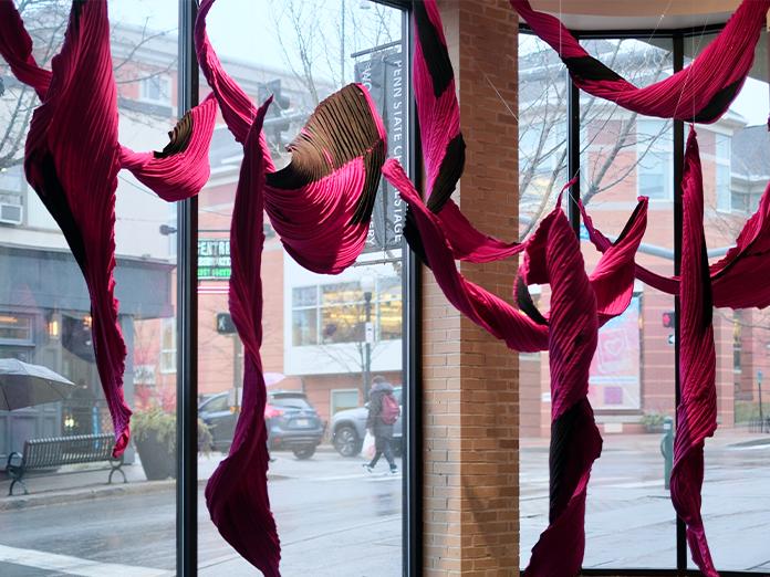 Crimson colored fabric draped in the window of a art gallery