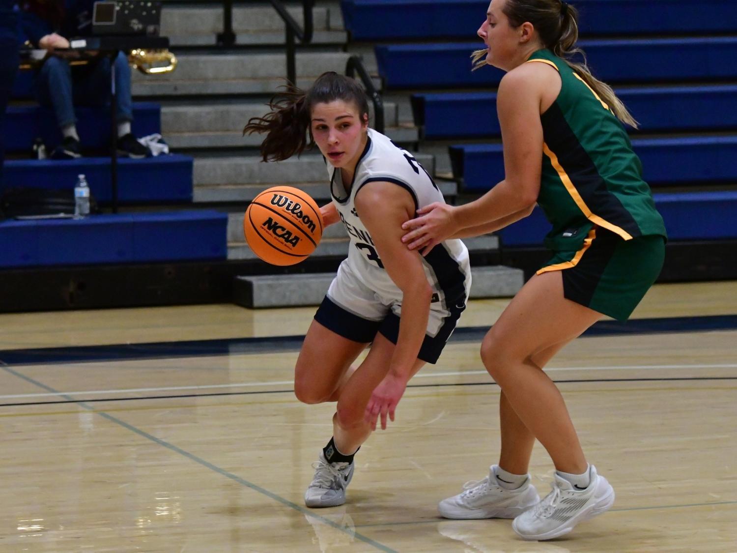 A member of the Penn State Behrend women's basketball team dribbles the ball past an opponent.