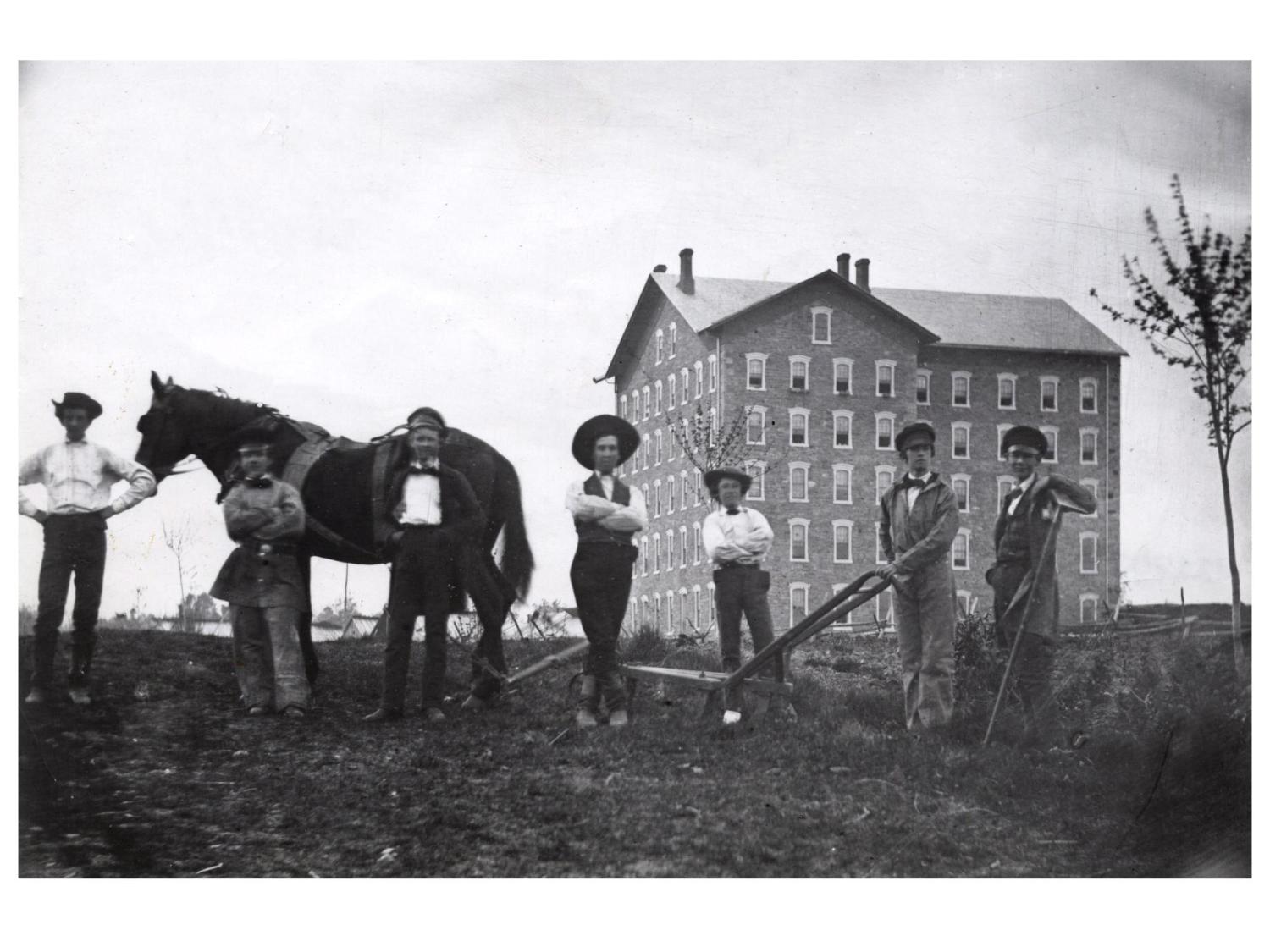 A black and white picture of students working outdoors in front of a building in 1859