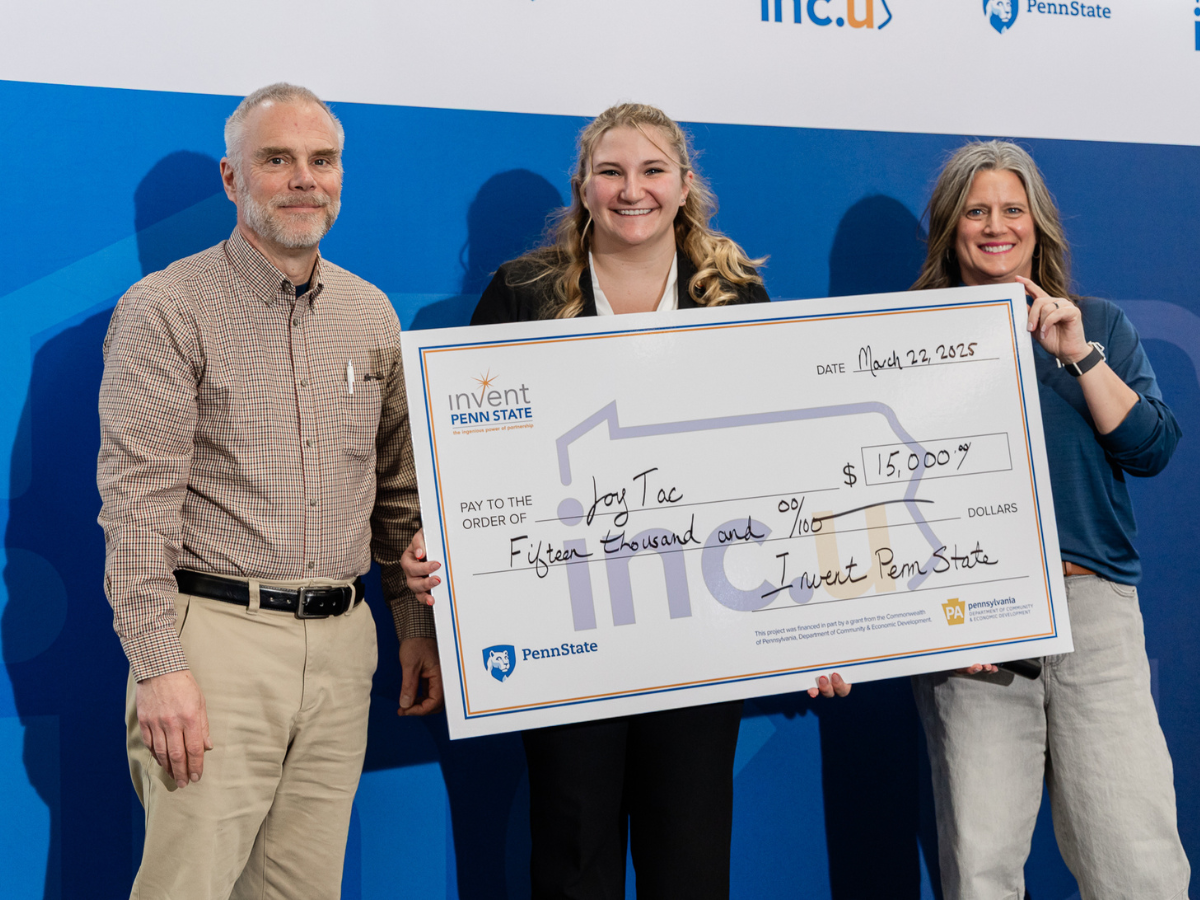 Three individuals stand holding oversized check made out to JoyTac