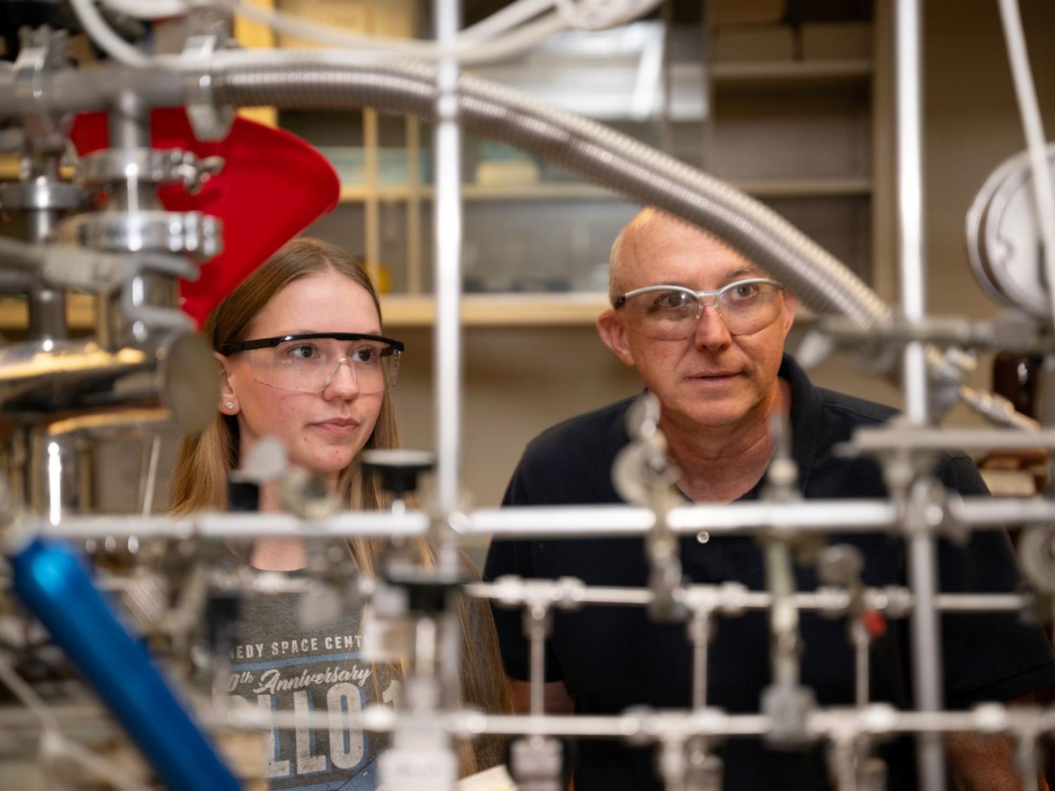 A student and a faculty member at Penn State Behrend look through a series of pipes in a custom-built spectrometer.