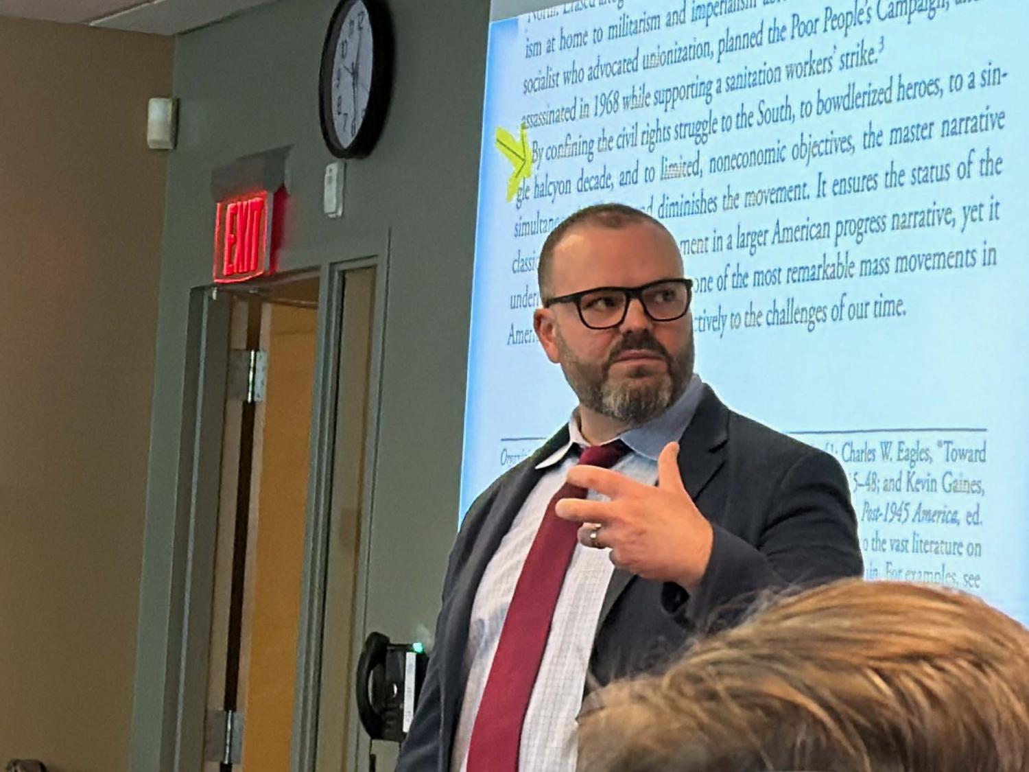 man speaking in front of a screen