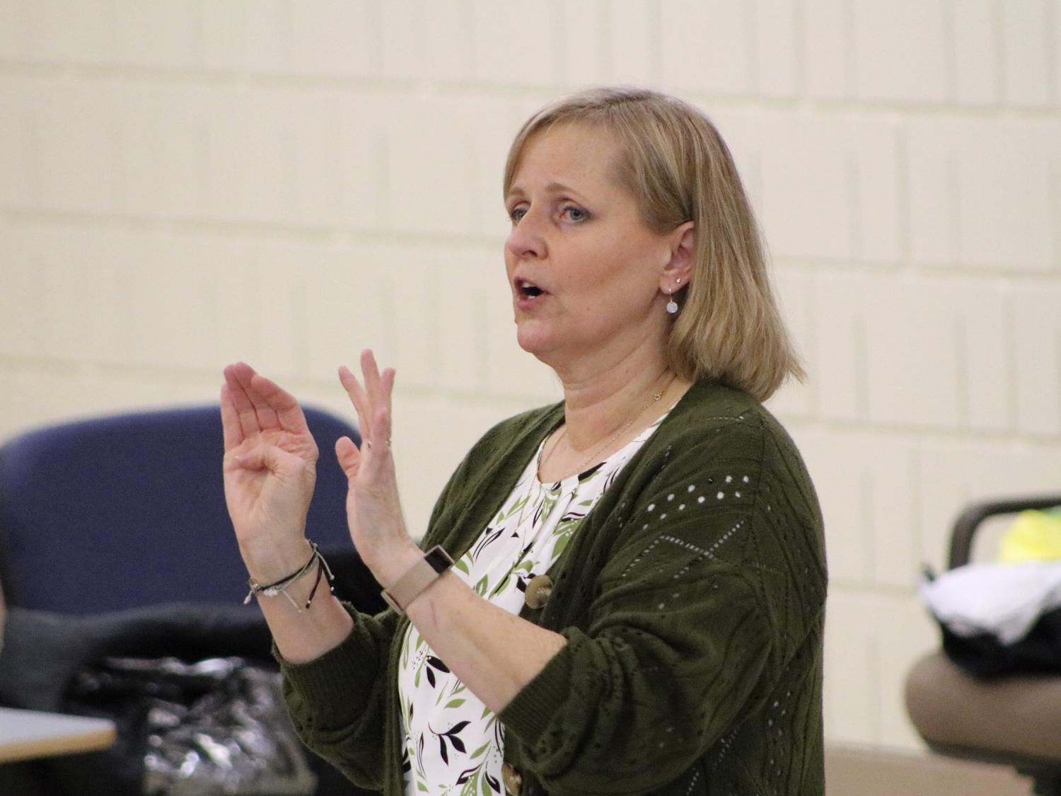 Michelle Kahl speaking and holding up both hands in front of her while giving a presentation.