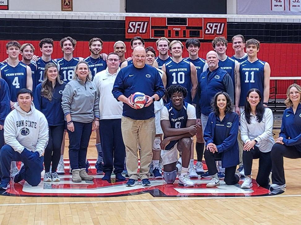 Coach with ball posing with team