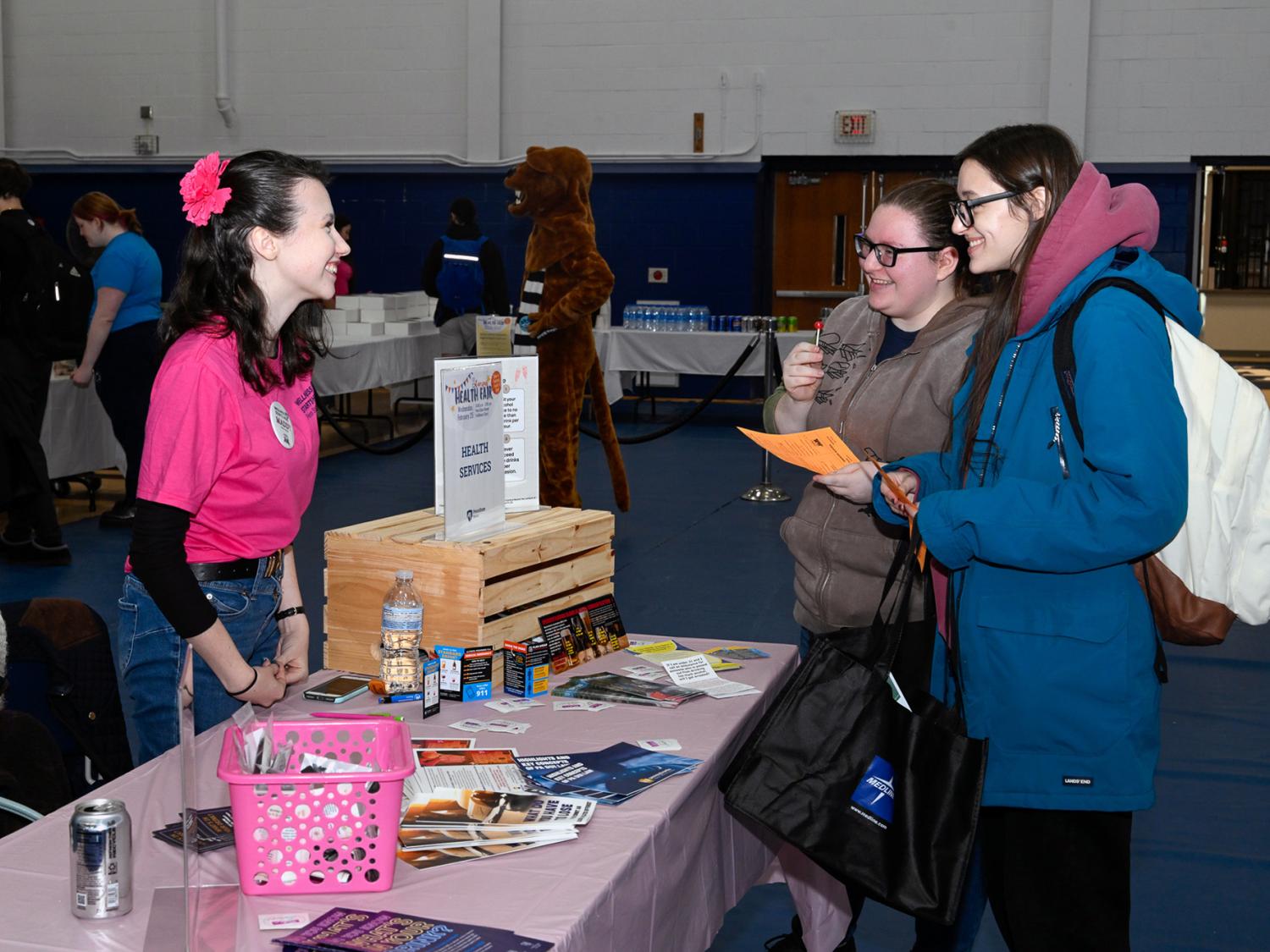 A student working at a table talks to two students