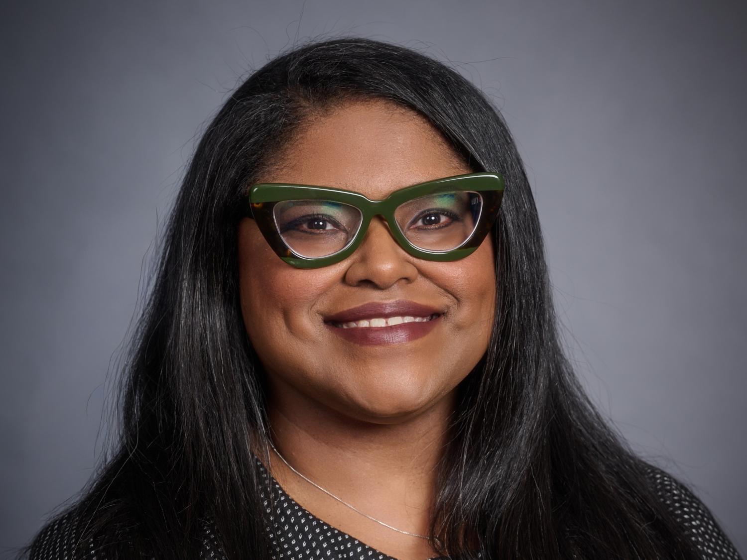 Headshot of person with long dark hair and green glasses
