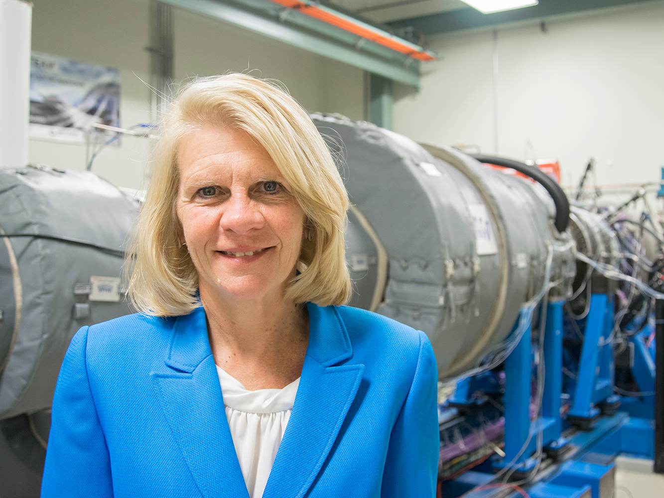 Karen Thole pictured in the Steady Thermal Aero Research Turbine Lab at Penn State, with a gas turbine engine in the background