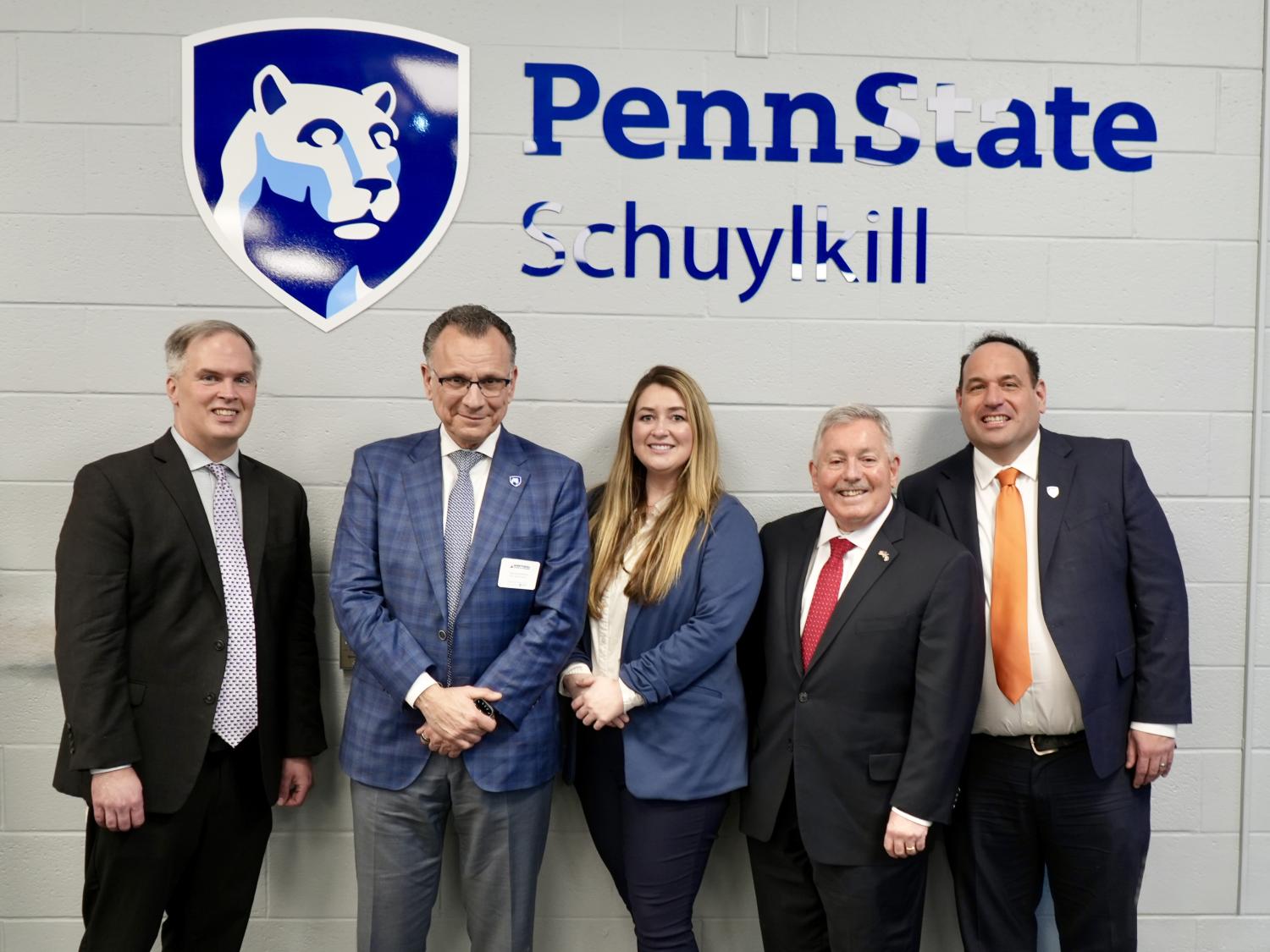 Five people stand for a photo in front of a sign that says Penn State Schuylkill