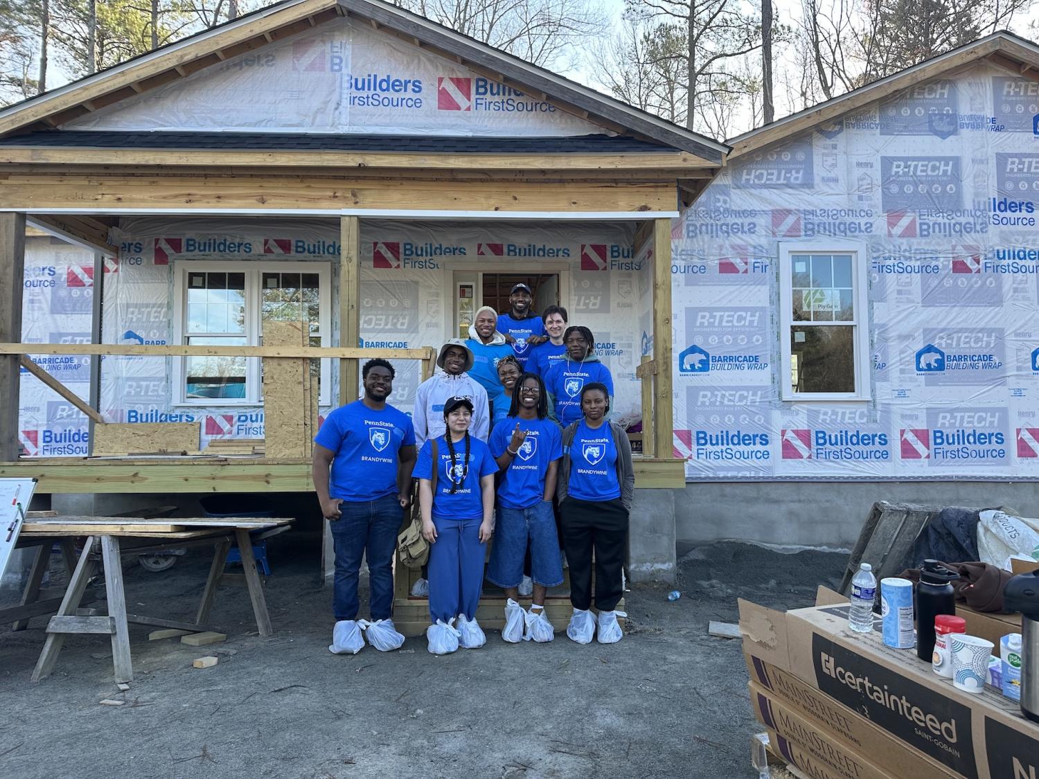 students standing in front of house