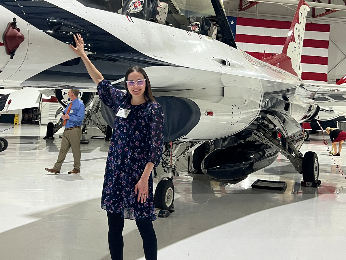 Courtney Cole standing in front of a stationary plane in Nellis Air Force Base.
