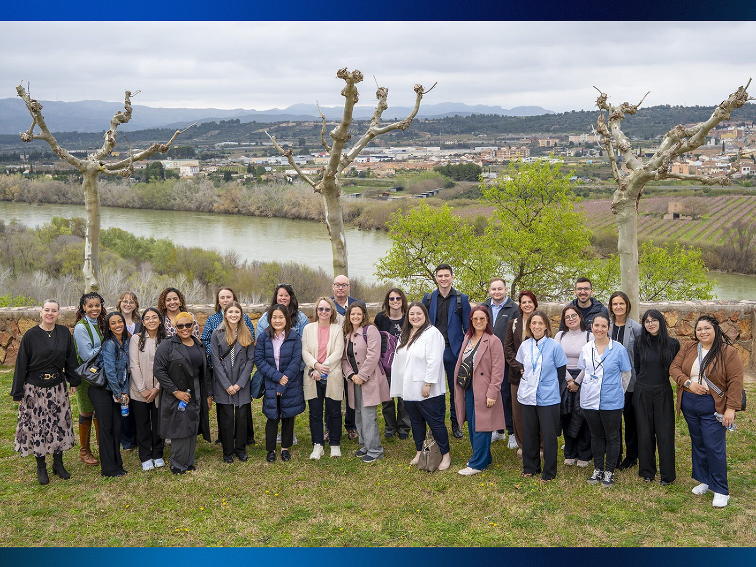 A group of people posing in front of a grassy valley area.
