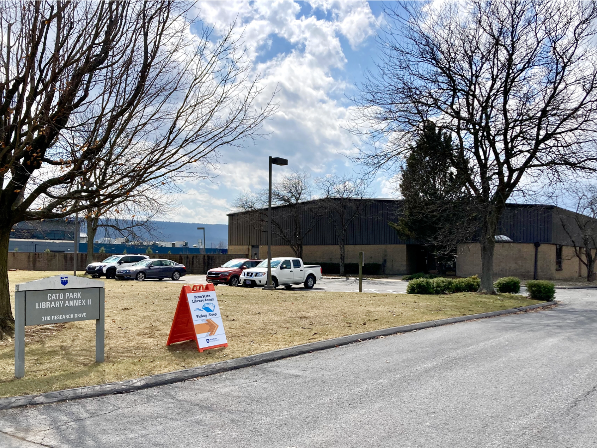 street sign, sandwich board and front of warehouse-style building in office park on sunny afternoon
