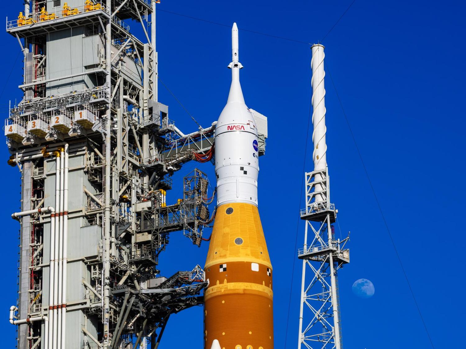 Artemis II on the launch pad, with the moon in the background.