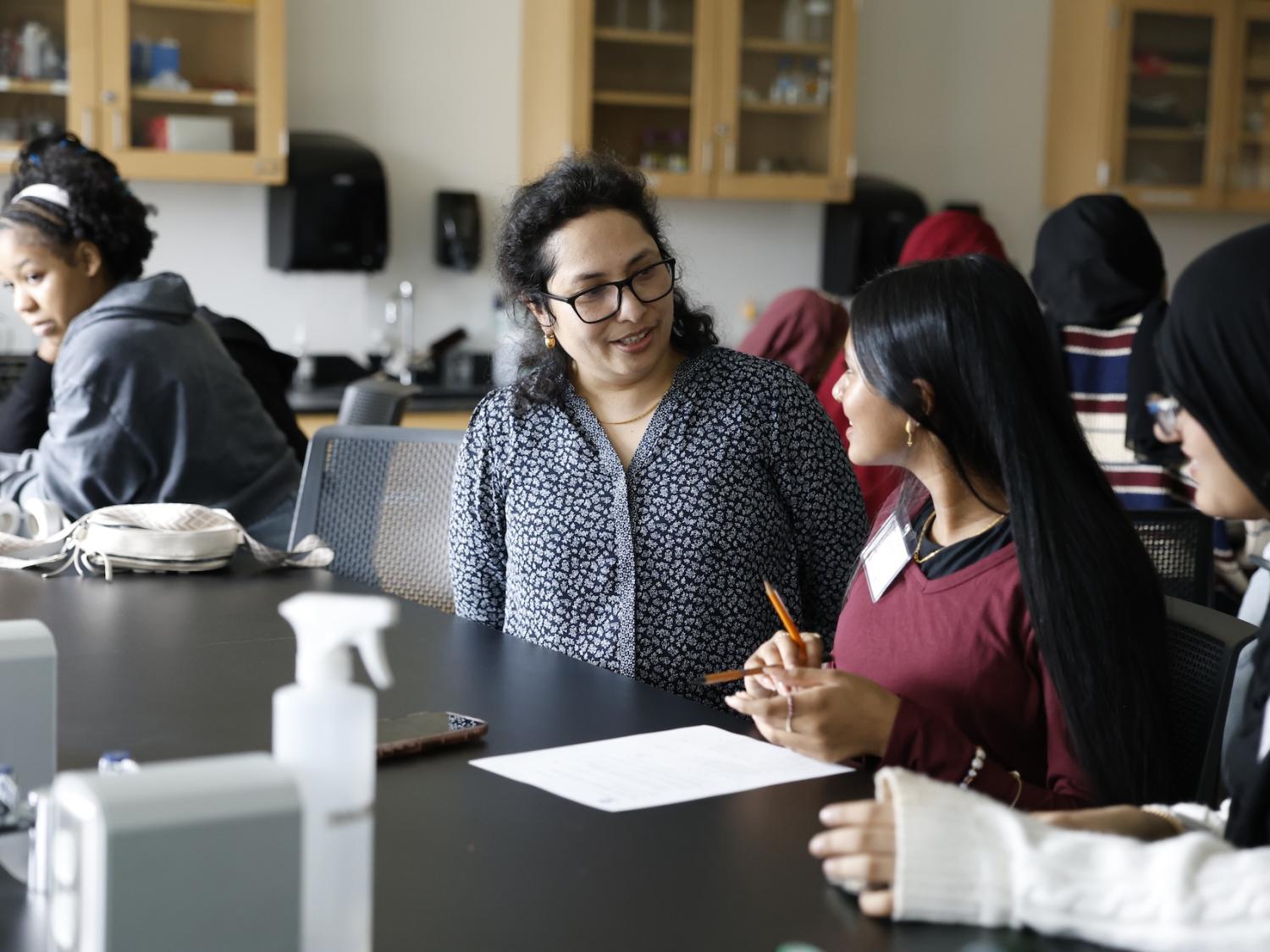 professor talking with high school students in a lab