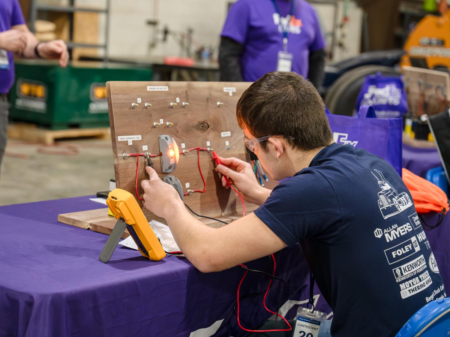 A student works on a circuit board at a table