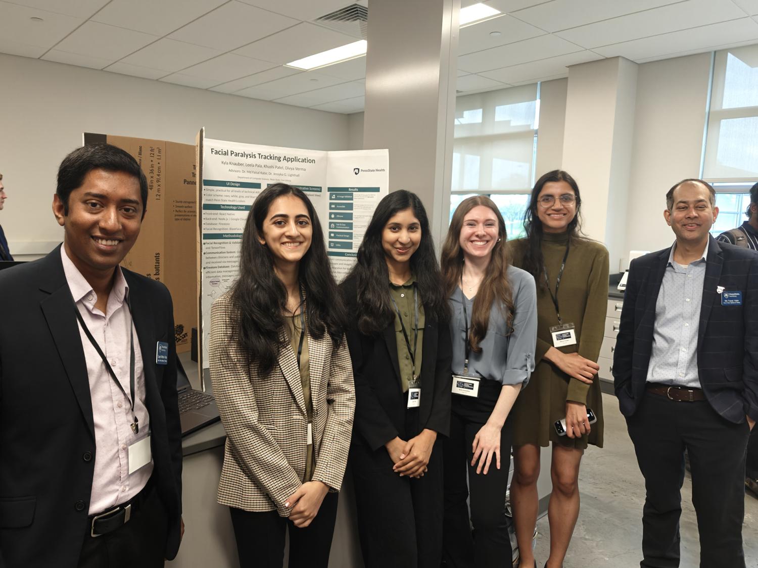 A group of six people stand in front of an academic poster