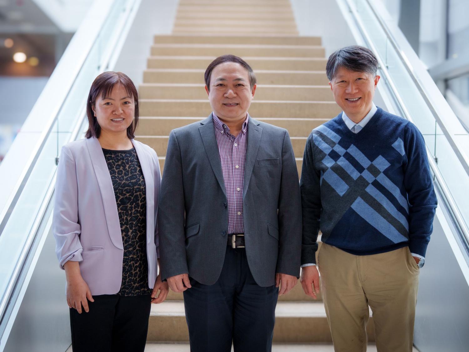 three people wearing business casual stand at the foot of a staircase