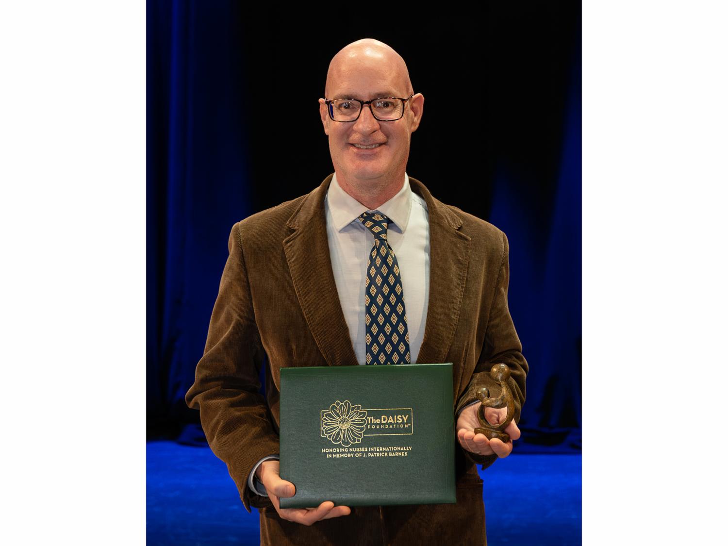 John Murphy holding an award and smiling