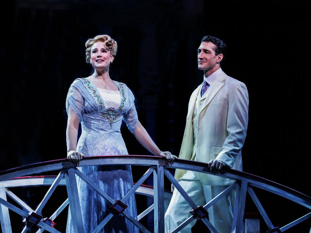 A man stands at a fence and sings while a man looks on.