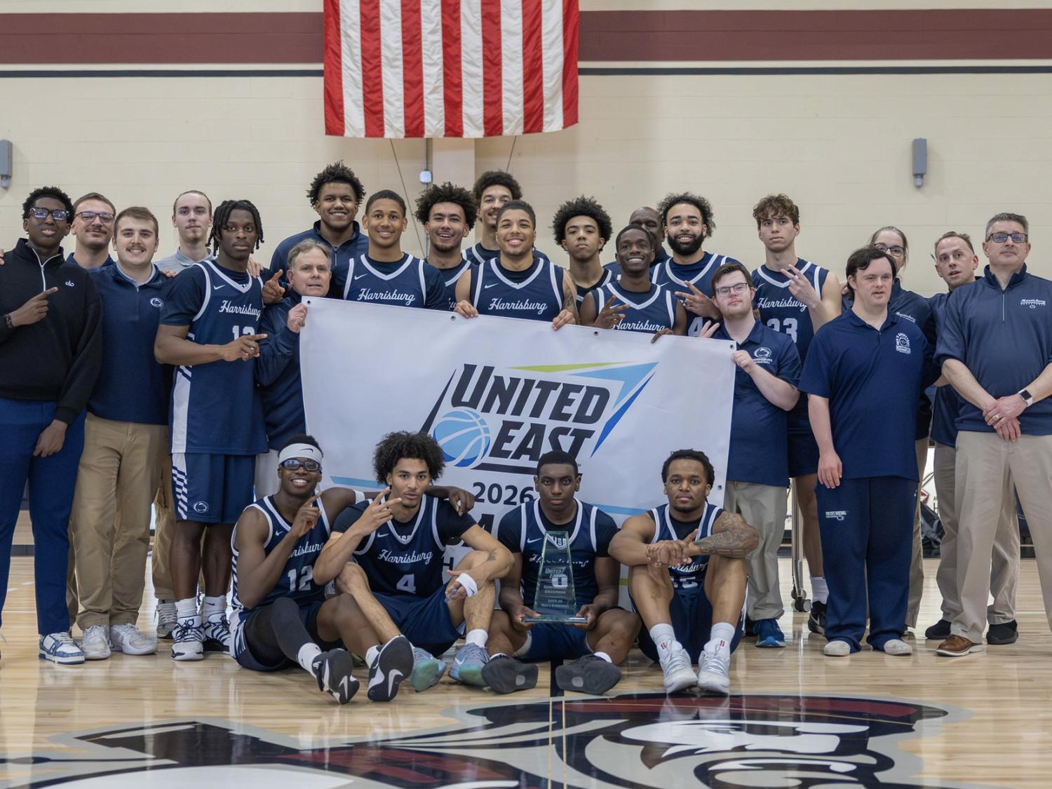 Penn State Harrisburg men's basketball team poses with a banner that says United East Championship