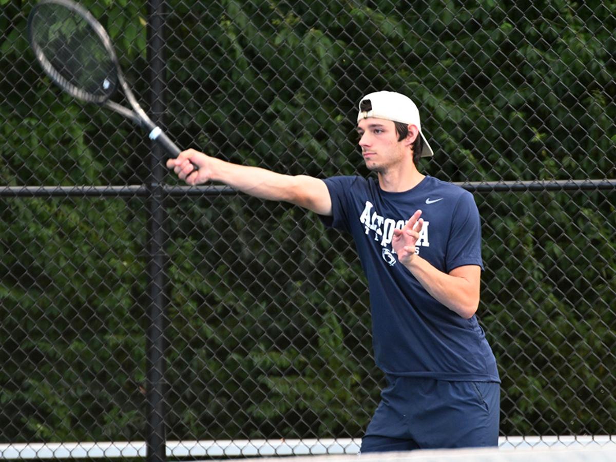 Penn State Altoona tennis player Nick Beard reaches out for a forehand shot during a match, focused and in motion on the court.