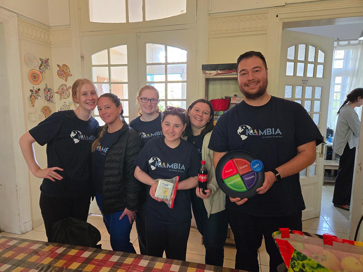 A group of Penn State nursing students pose together during a Global Brigades service trip, holding nutrition materials and supplies.