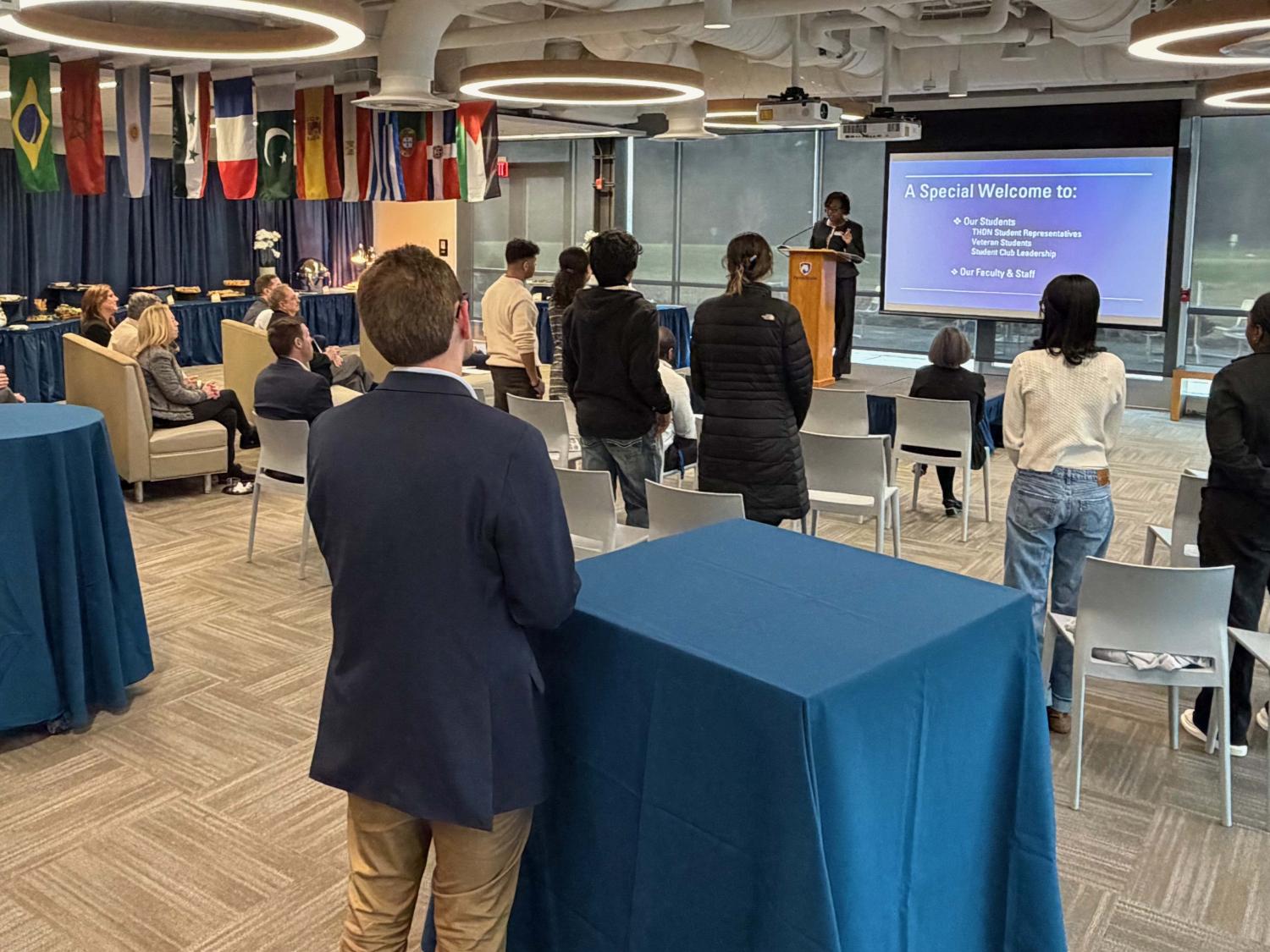 group of people sitting and standing looking at the speaker at a podium