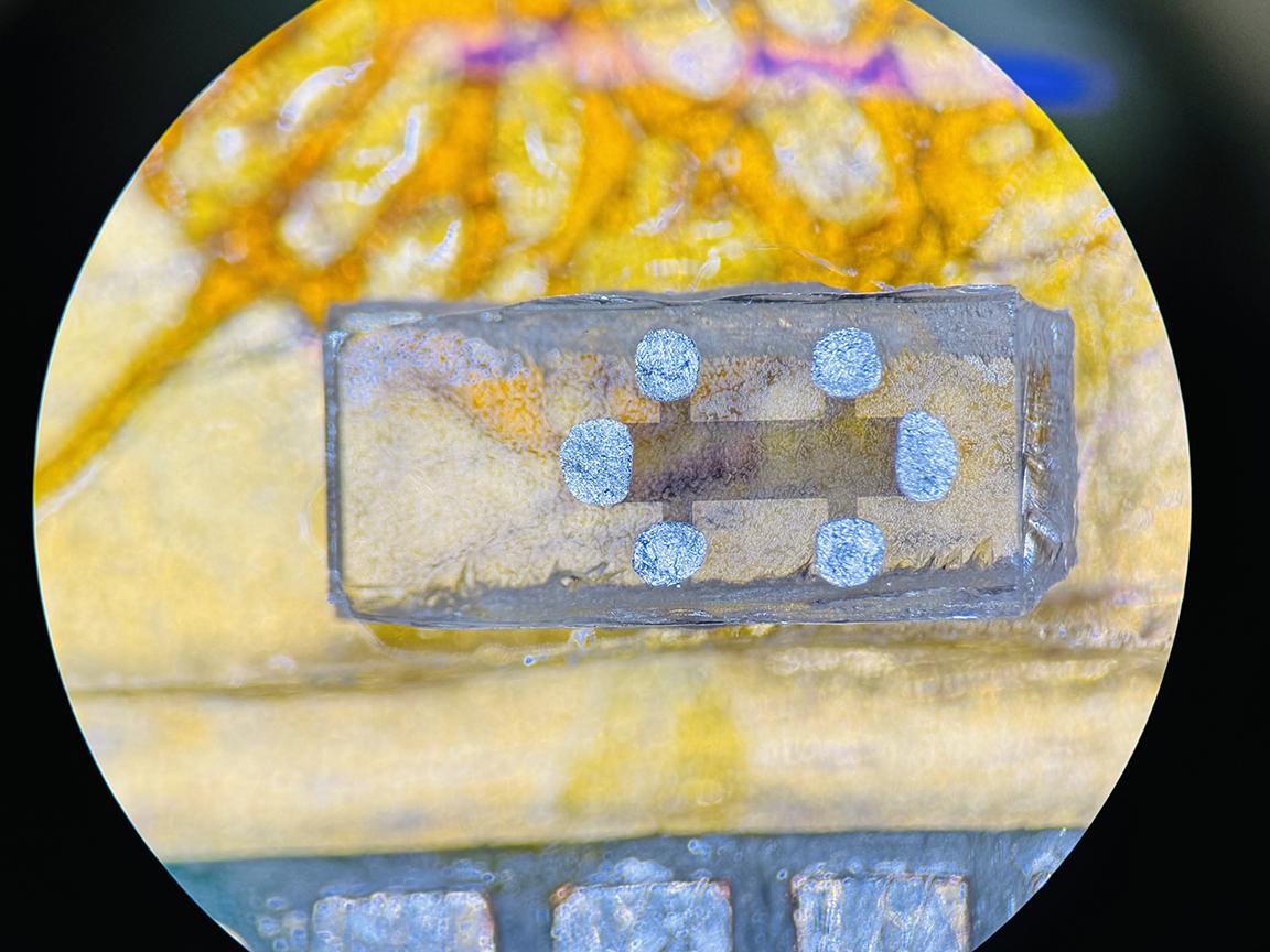 Circular image of thin film sample of iron telluride, which appears as double cross shaped dark area on clear backing.